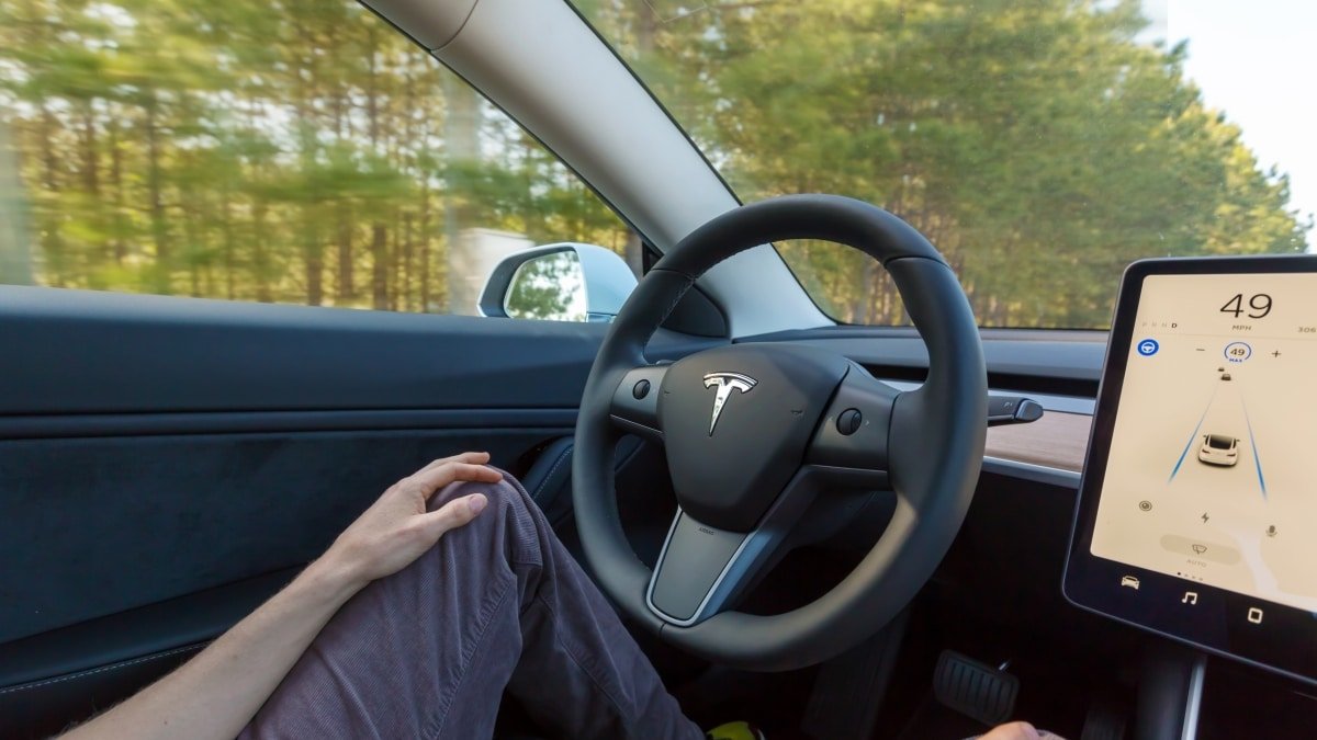 Motorista dirigindo um Tesla Model 3 com o Autopilot ativado