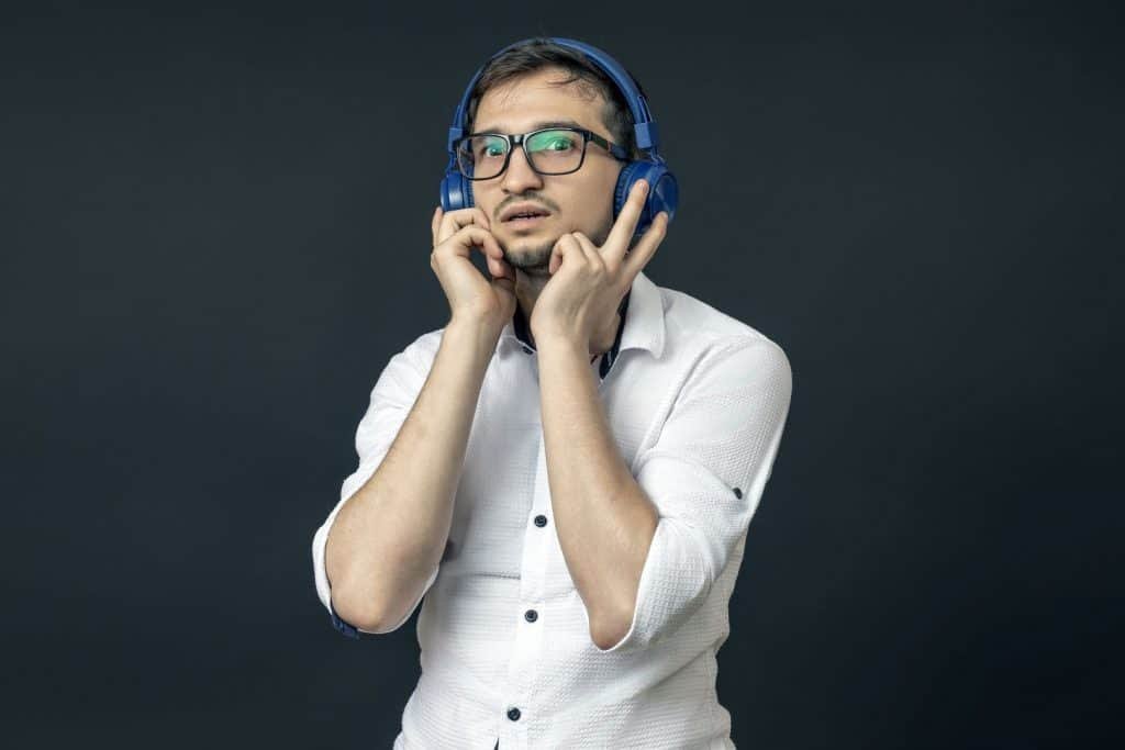 um jovem de óculos fica surpreso com a música que ouviu nos fones de ouvido e está em um fundo preto